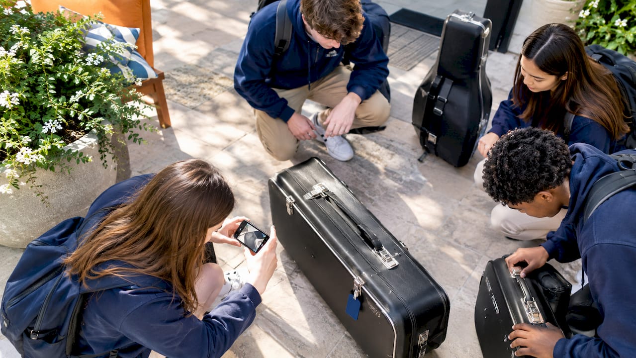 students photographing instrument cases after arrival